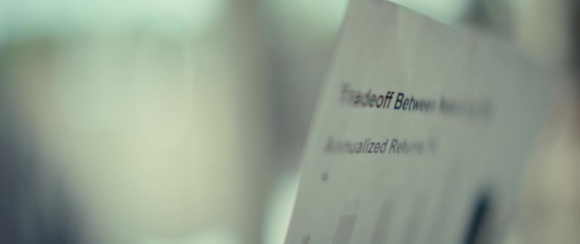 A young man examines a financial document before the camera pans to an extreme closeup of his eyes as he focuses on the data in a brightly lit room