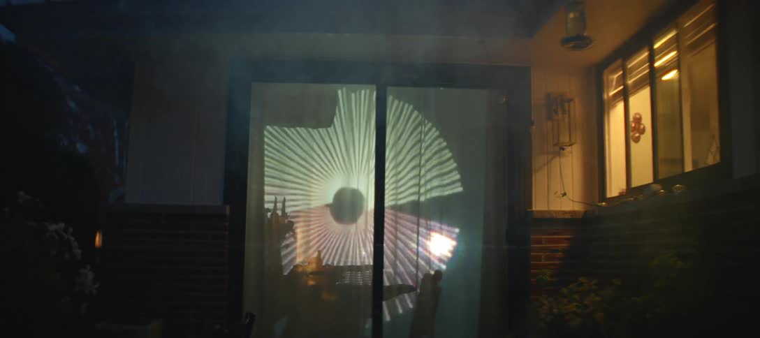 Glass door at night with a circular light projection inside the house