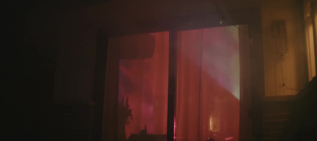 Glass door at night with closed curtains and colored light projected inside