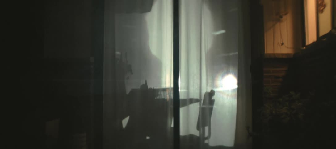 A view from the outside of a window with flashing lights in the room