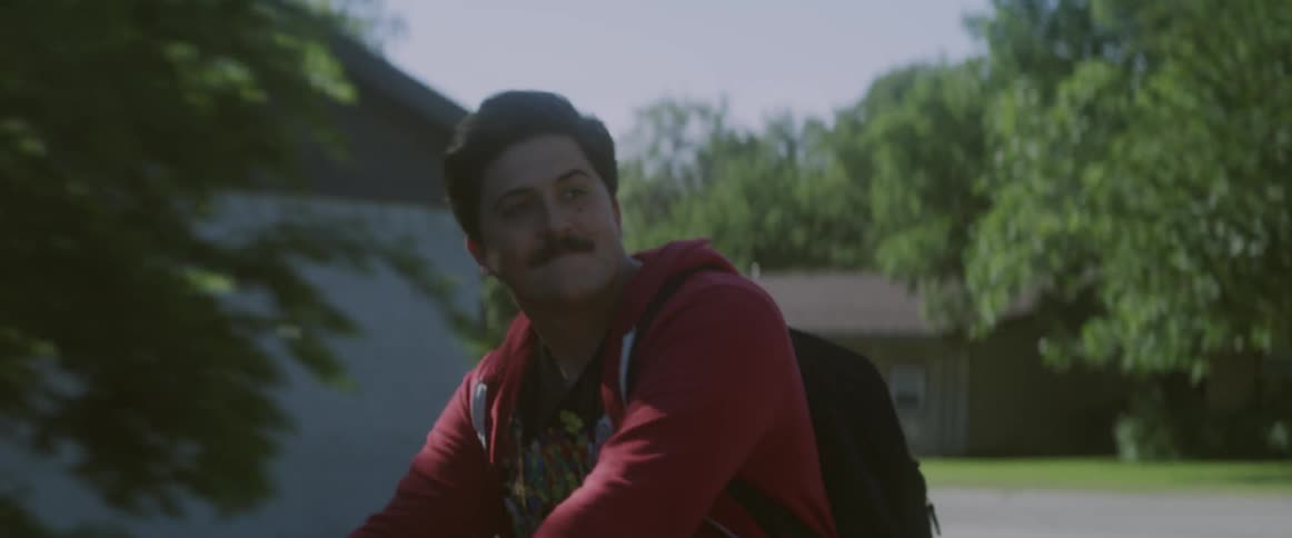 A man with a mustache rides a bike by some trees