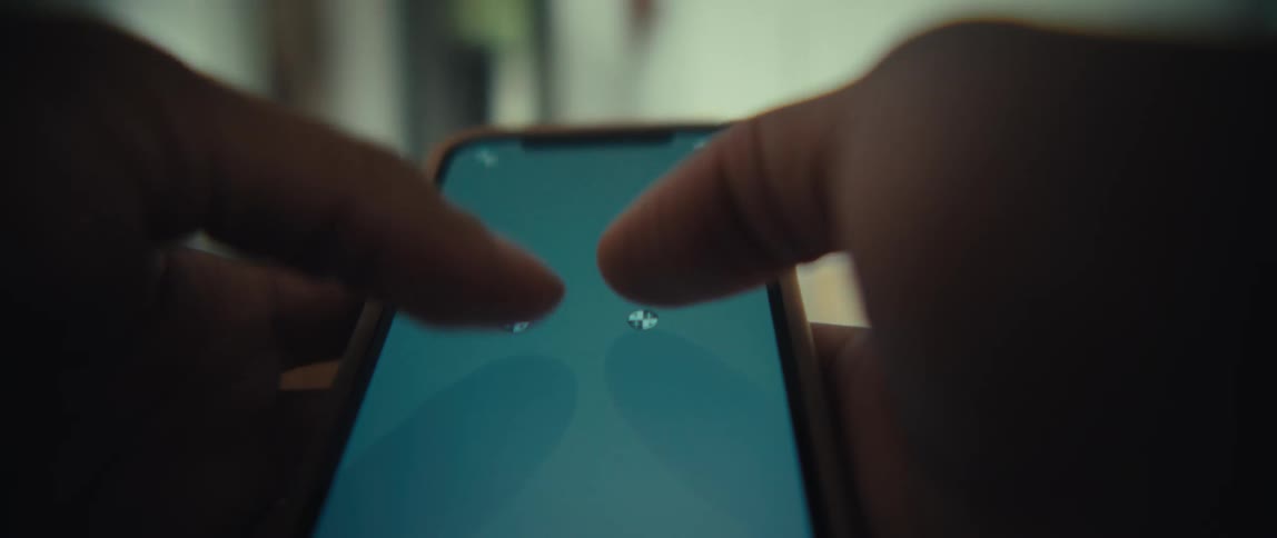 A closeup shot captures a persons thumbs rapidly typing on a smartphone screen which displays a bright blue interfacethe lowangle perspective highlights the quick rhythmic movement of the fingers against the backdrop of a softly blurred indoor env