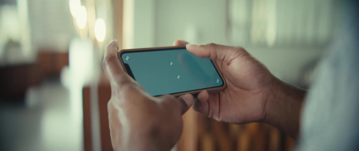 Man standing in a room holding a smart phone sideways with both hands