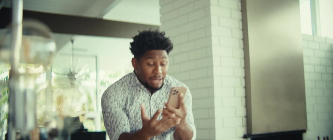 The man raises his arms and yells while holding his cell phone