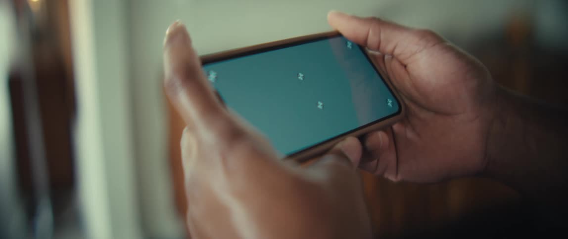 A man holds a smartphone horizontally with both hands in a close up shot in an indoor setting