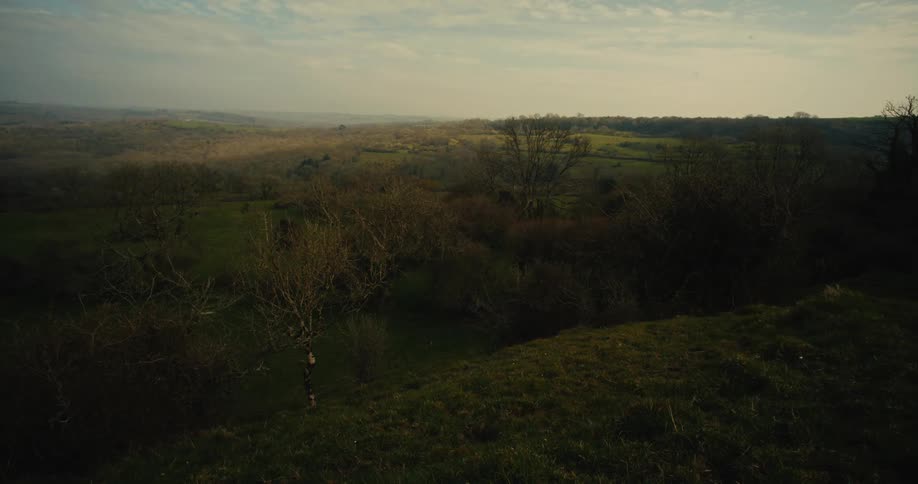 A wide elevated shot of a rolling countryside landscape during what appears to be the golden hour