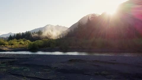 Mist rises from the forest in front of mountains
