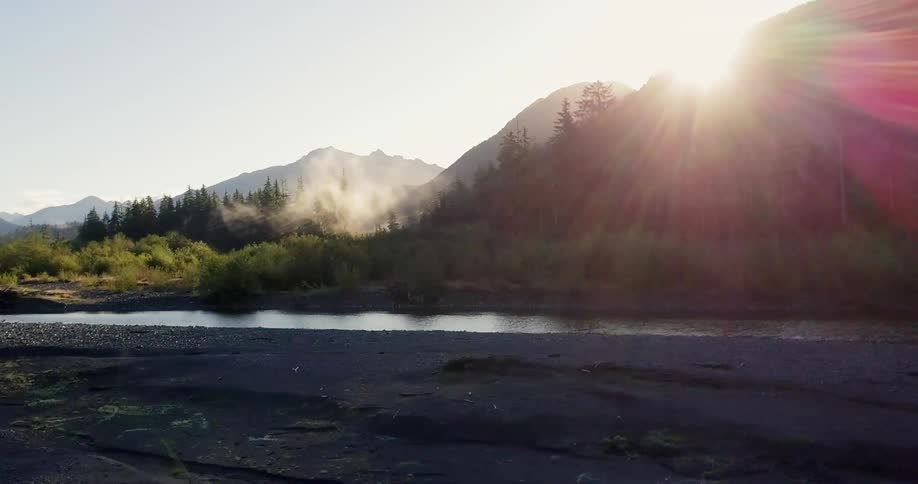 Mist rises from the forest in front of mountains