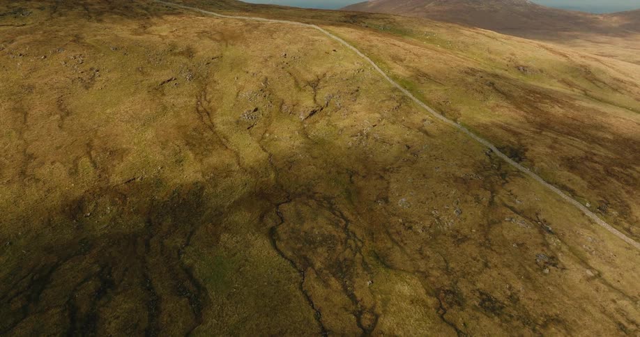 Aerial view of a large mountain with a paved path