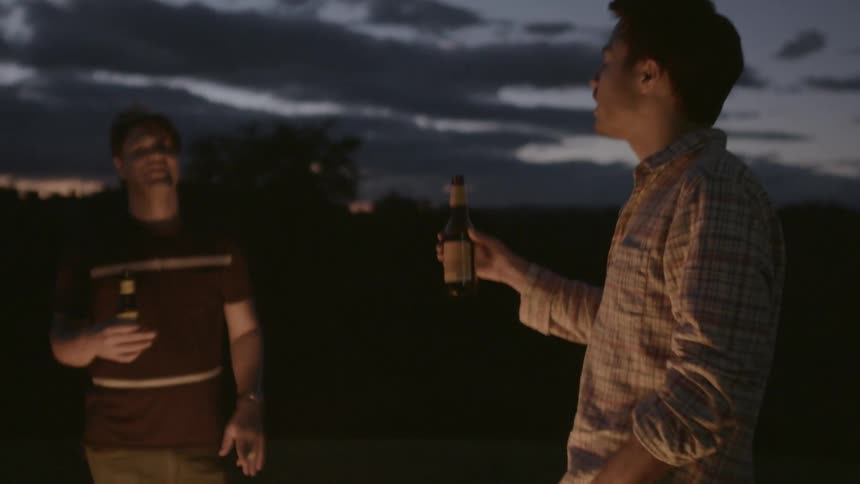 People stand by a campfire drinking beers