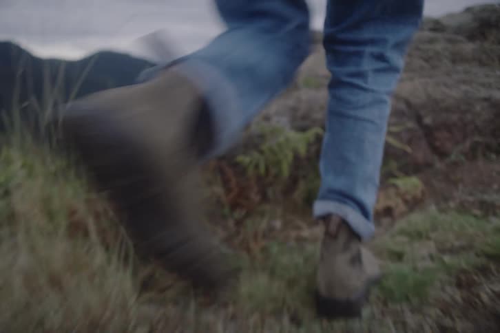 Human legs hiking on a mountain and climbing rocks outdoors during day time