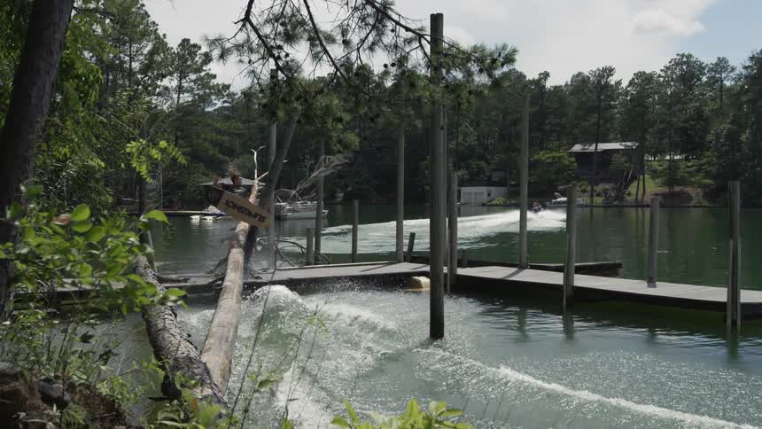 Wake boarding man jumps over a dock and falls into the water