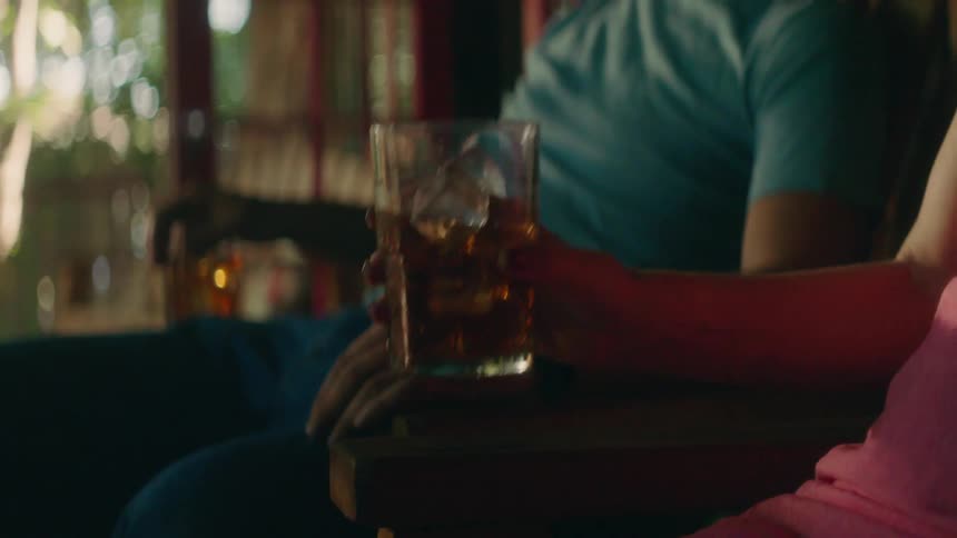 Woman sipping from an iced drink while sitting indoors next to a man