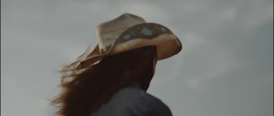 A girl is horseback riding on a windy day