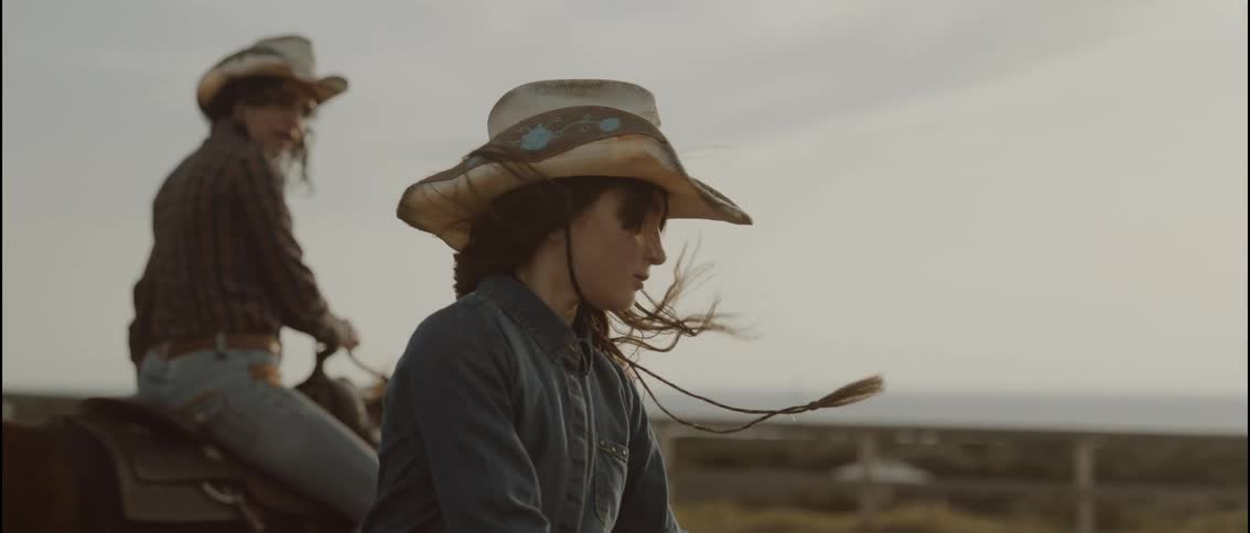A woman and her daughter riding horses outdoors