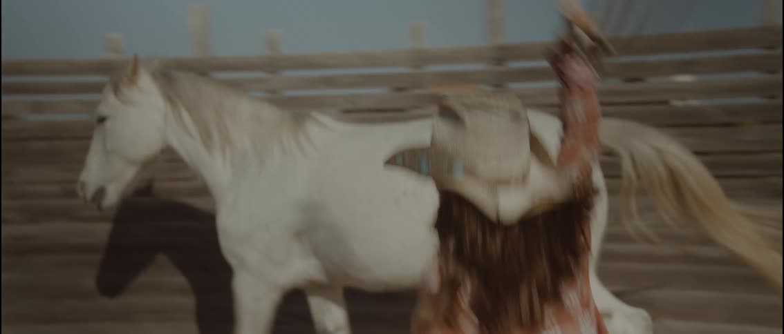 Teenager chases a horse in the corral with a lasso during the daytime