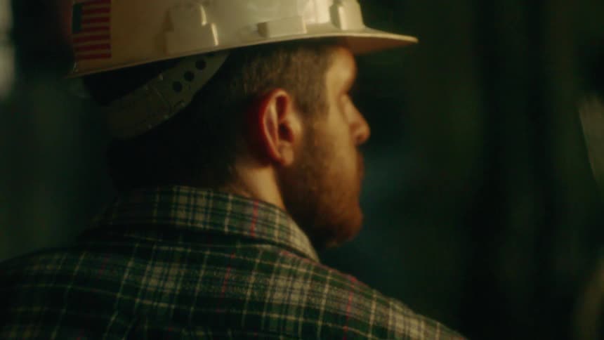 A worker wears a hardhat with an american flag on the back