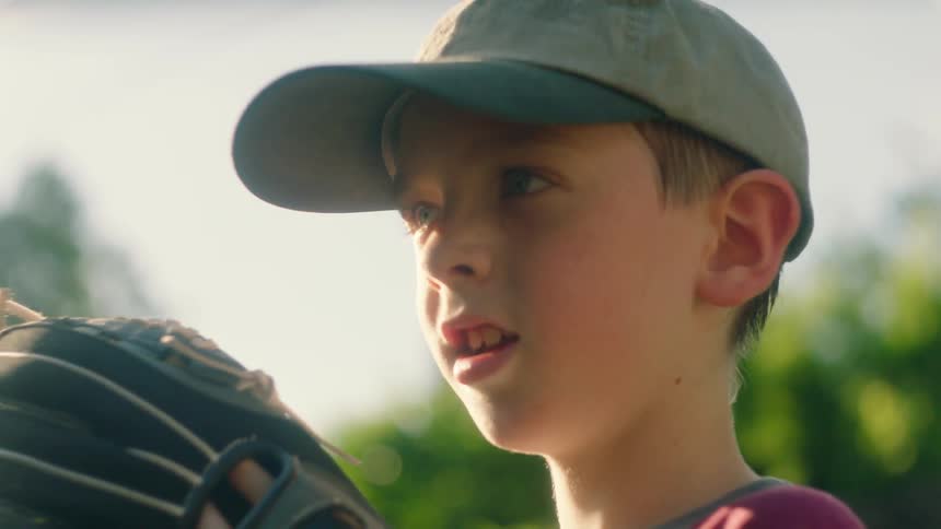 Boy in a baseball outfit working out his glove outdoors