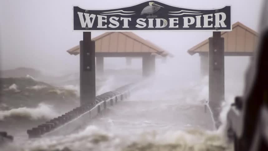 Splashing waves crash over the west side pier during a hurricane
