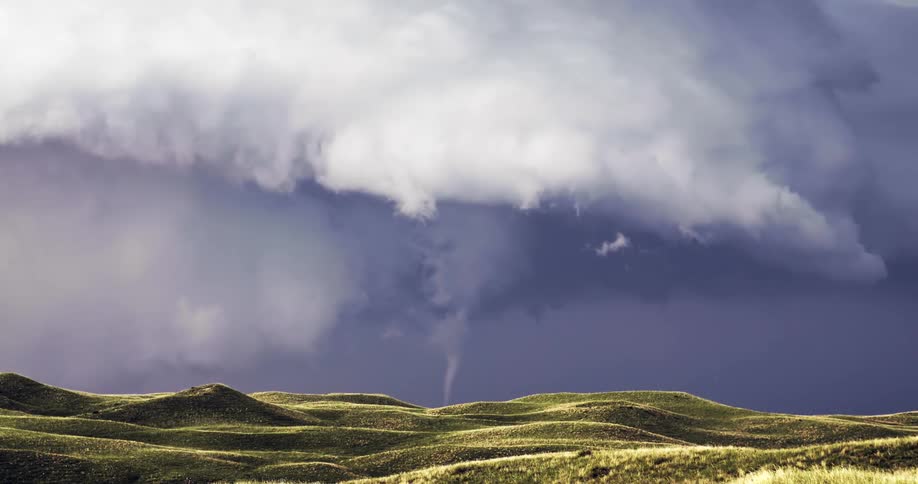 Funnel cloud moves across rural hills on the landscape