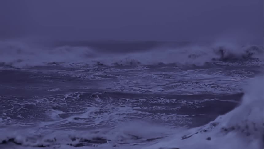 Violent ocean waves crash against each other on a cloudy evening