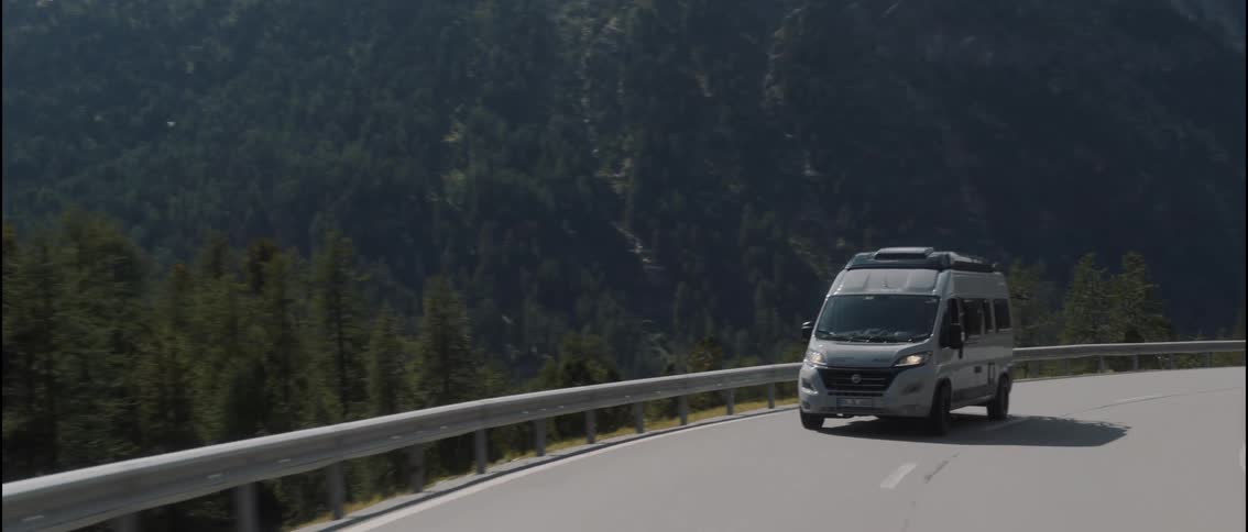 The van is driving on the curved mountain road