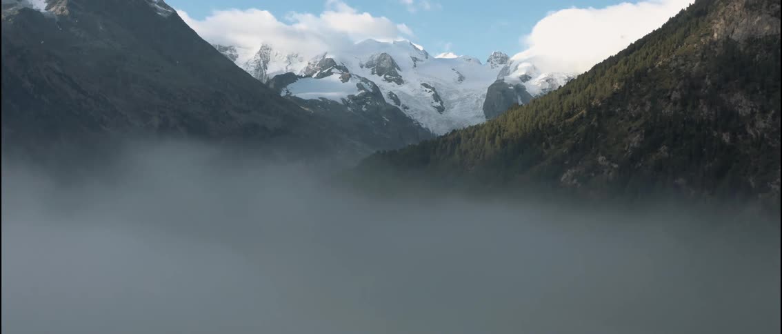 Valley covered in mist surrounded by mountains outdoors during day time