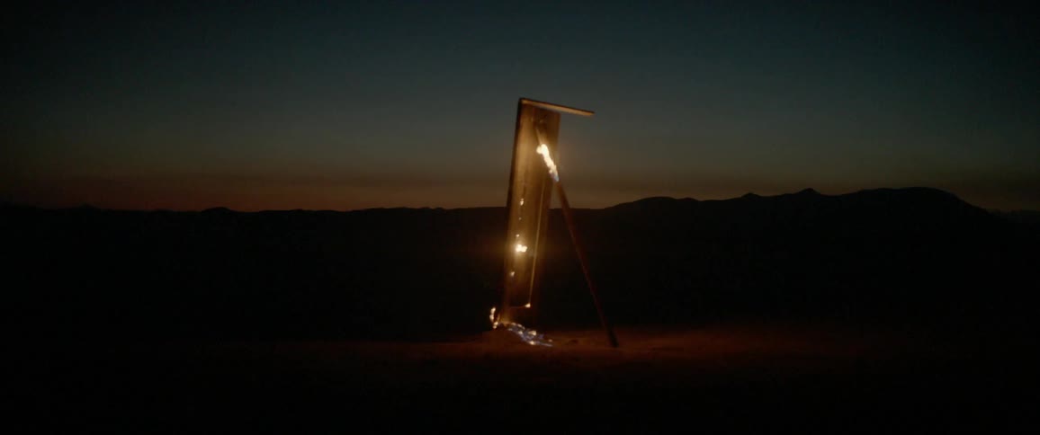 Wooden table burning outdoors as it's vertical and leaning on a longboard