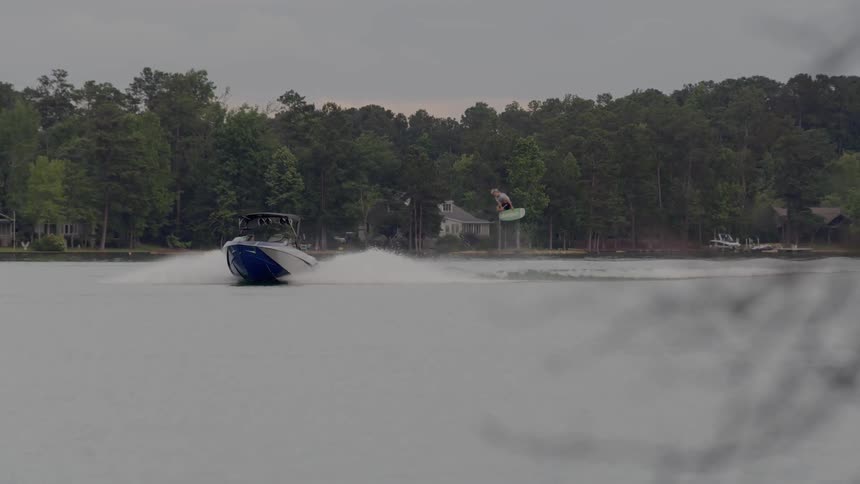 Person water skiing in a river being pulled by a small boat