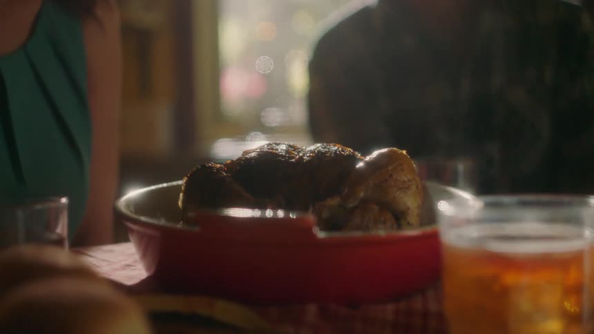 Man and woman sitting at dinner table with cooked chicken