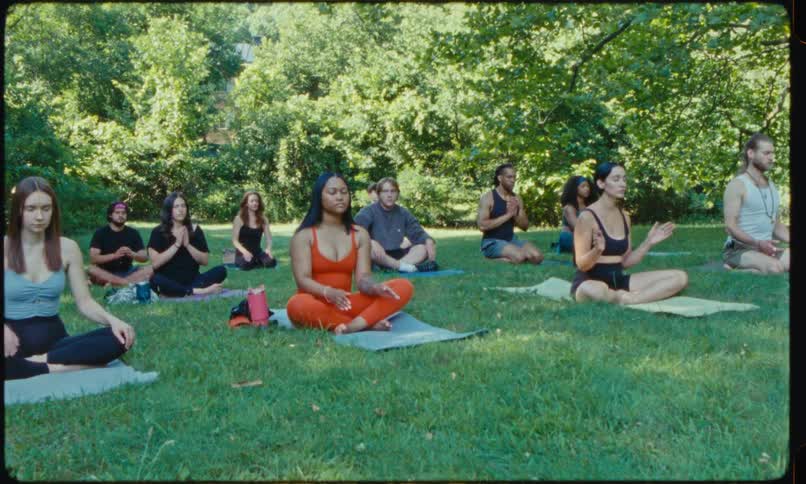 Group of people meditates during a yoga class in the park on a summer day