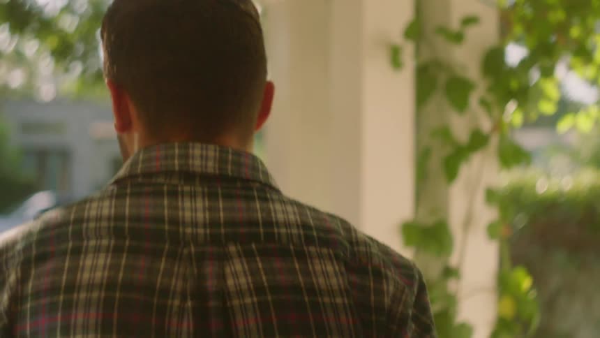 A man opens the front door of a house and walks outside