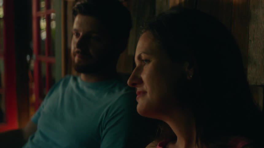Man and woman sitting on porch look at each other and smile