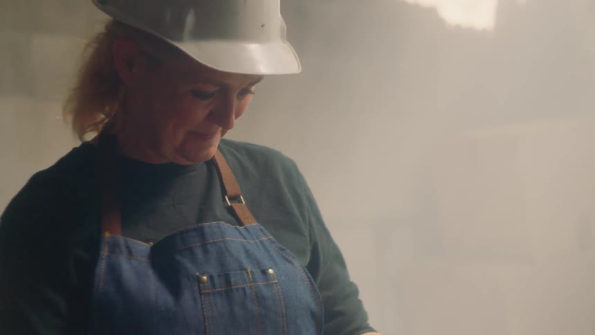 Woman wearing a hard hat smiles and looks down
