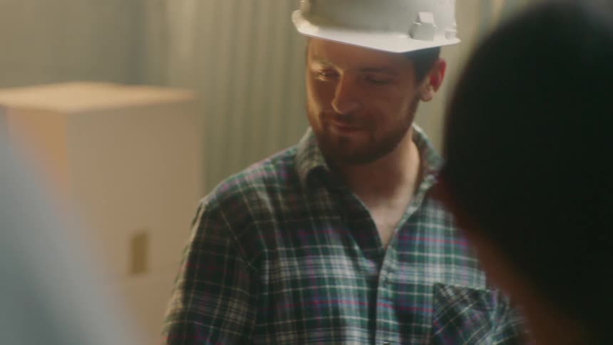 A man wearing a hardhat smiles and talks with workers