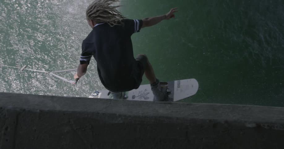Surfing man scales a wall and splashes back into the water