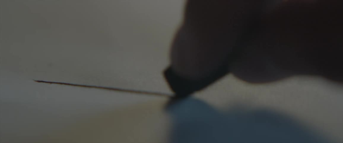 Person draws a line on a white paper with black pastel pencil