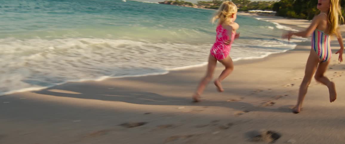 Two girls running on the beach sand by the sea