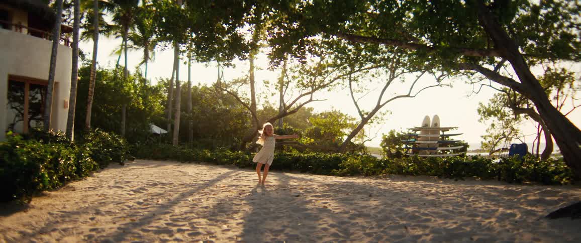 Little girl playing and dancing next to a building on the coast as another girl runs to join her
