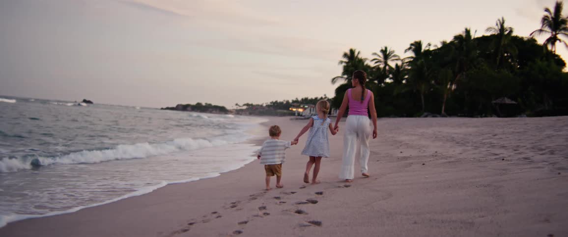 A mother and two kids walking on the beach