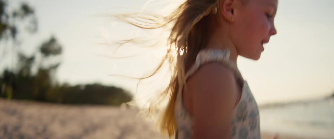 The girl raises her arms and runs on the beach