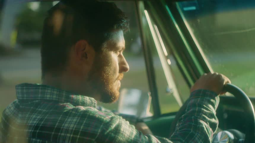 A man drives in a car on a sunny day