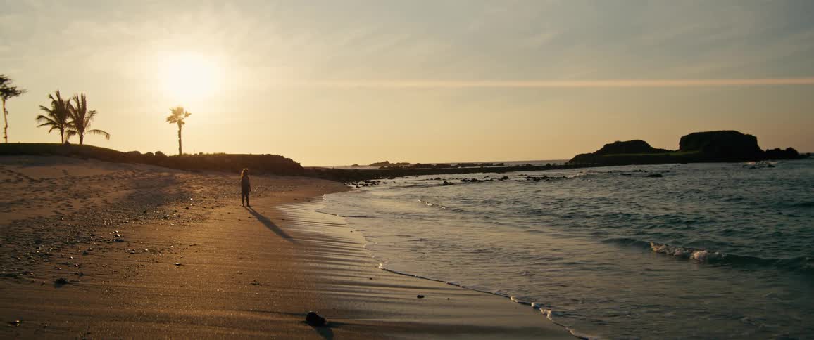 Young blonde girl runs on the beach near sunset in the summer