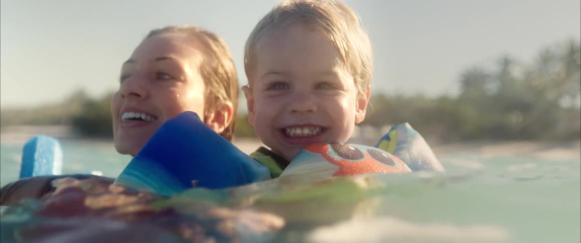 Woman and boy smiling in the sea water with inflatable floaties