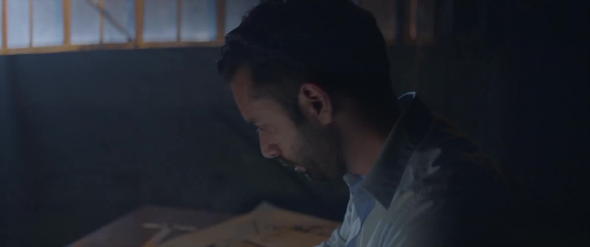 Man sits at a desk looking down at his work