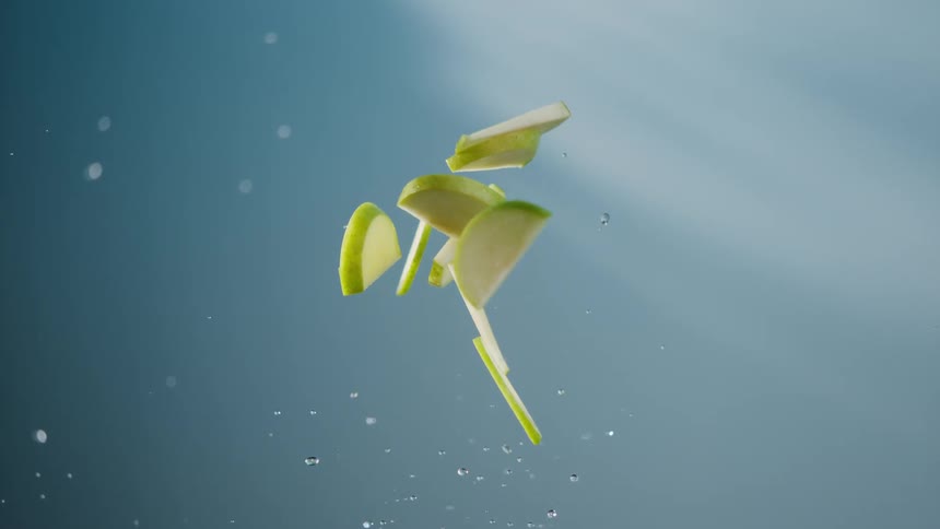 Lime slices suspended in the air with water droplets around them