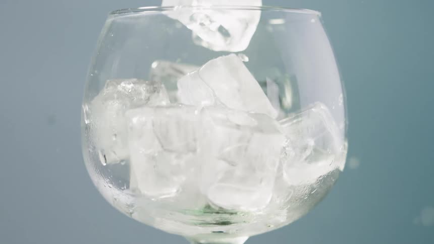Ice falling into a transparent glass bowl