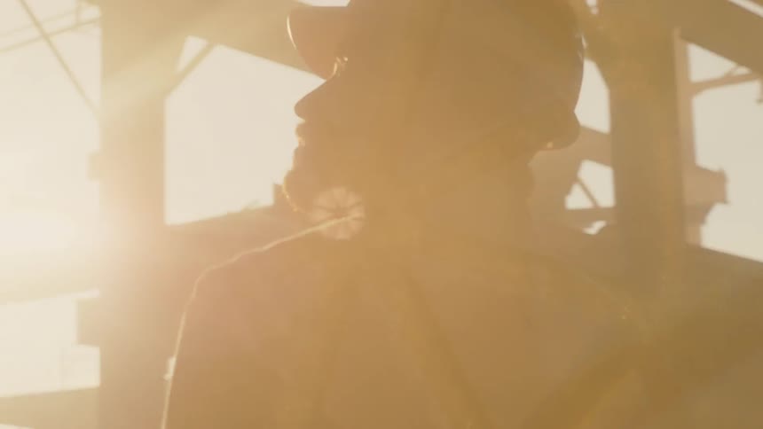 A worker wears a hardhat outside at sunset