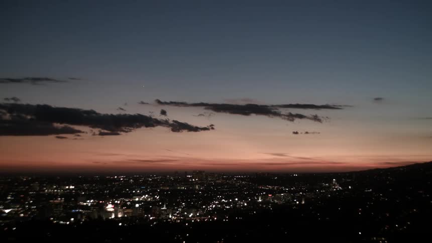 Panoramic view of a city lit up at dusk with sky in shades of orange and blue