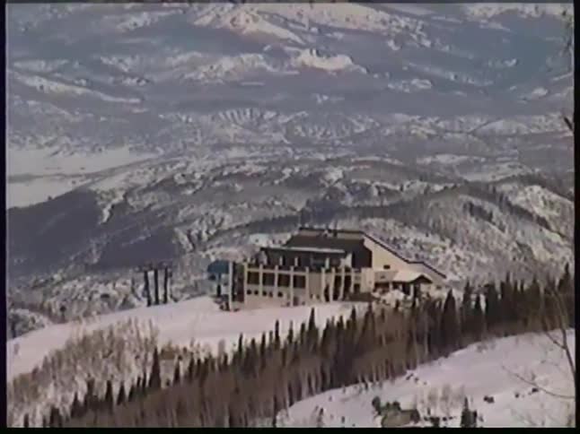 Chairlift station next to a forest with mountains on the background outdoors during day time